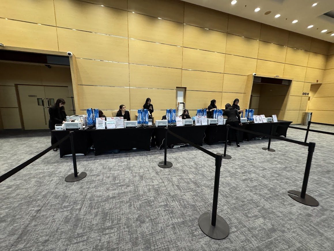 Wide onsite event registration counter with equipment, queue ropes and service crew